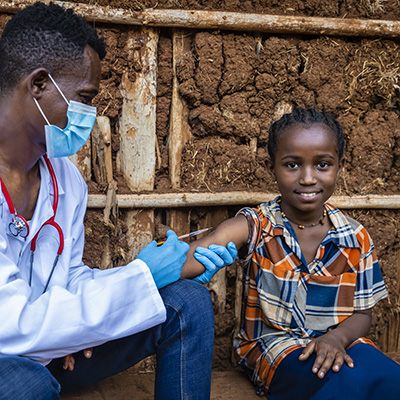 Doctor is doing an injection to young African girl in small village, East Africa